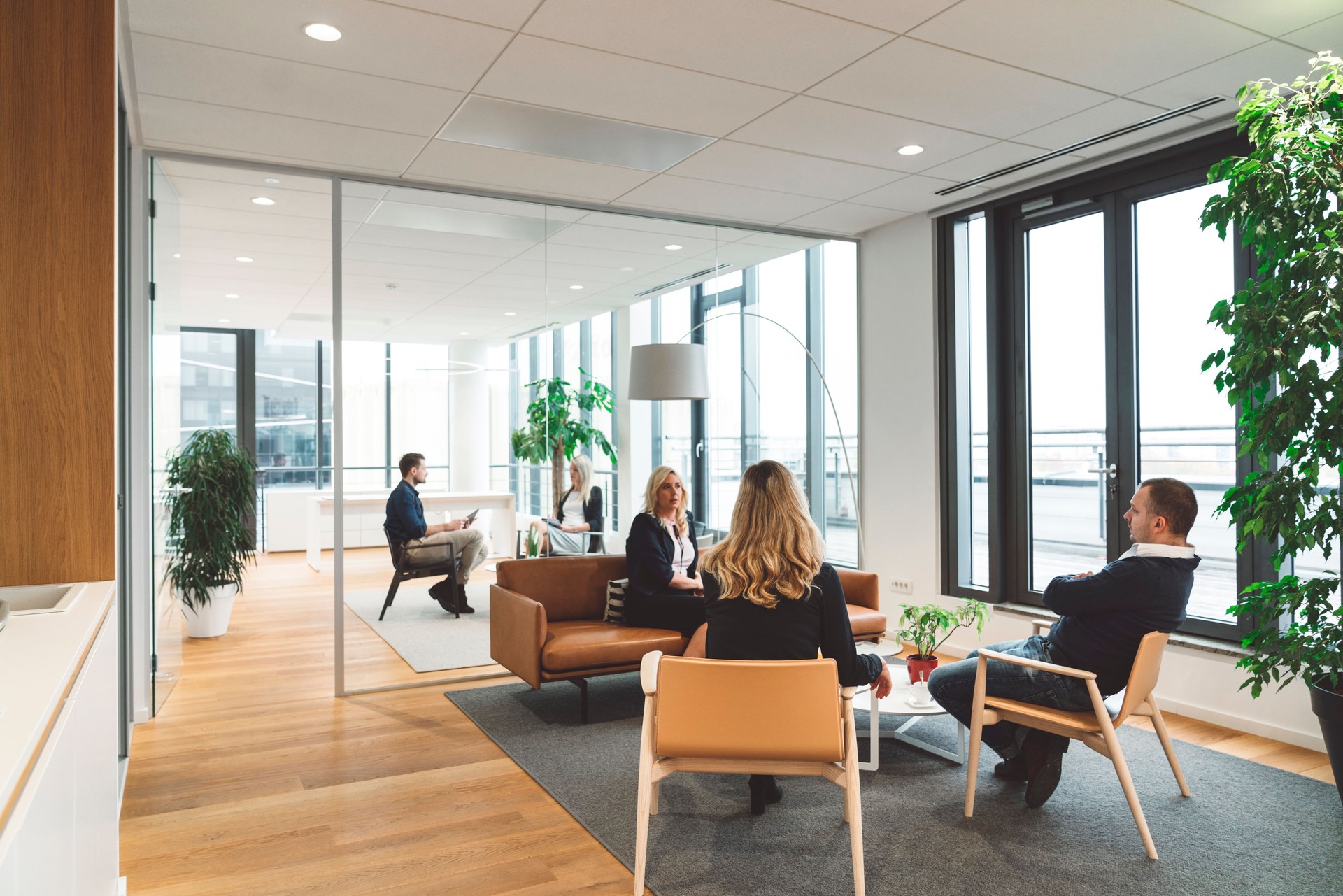 Business people having multiple meetings in modern office with glass walls